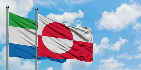 Sierra Leone and Greenland flag waving in the wind against white cloudy blue sky together....