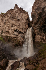 Fototapeta na wymiar mountain waterfall among rocky landscape and splashes