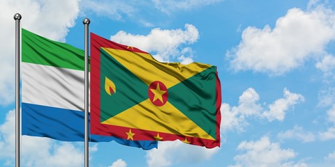 Sierra Leone and Grenada flag waving in the wind against white cloudy blue sky together. Diplomacy...