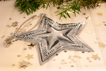 stella d'argento su tovaglia bianca con stelle e rami di pino