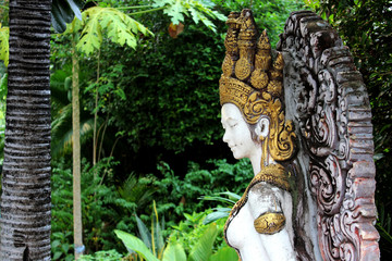 A beautiful white angel statue wearing a golden crown on the head in the garden