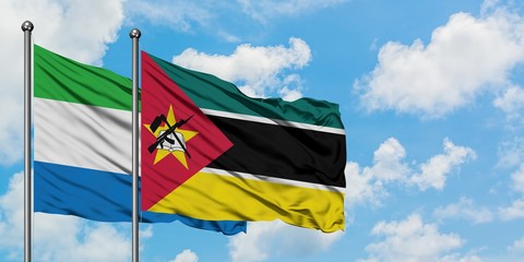 Sierra Leone and Mozambique flag waving in the wind against white cloudy blue sky together. Diplomacy concept, international relations.