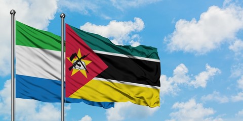 Sierra Leone and Mozambique flag waving in the wind against white cloudy blue sky together....