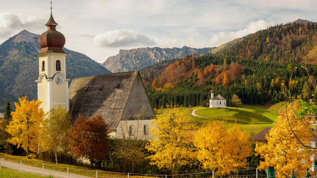 Church of Achenkirch in Tyrol in the golden light of autumn with yellow trees