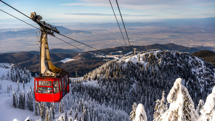 Poiana Brasov, Romania - cable car  ski resort, skiers and snowboarders enjoy the ski slopes in winter resort with trees covered in snow. - obrazy, fototapety, plakaty