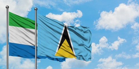 Sierra Leone and Saint Lucia flag waving in the wind against white cloudy blue sky together. Diplomacy concept, international relations.