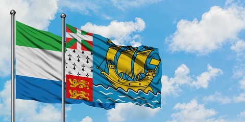 Sierra Leone and Saint Pierre And Miquelon flag waving in the wind against white cloudy blue sky together. Diplomacy concept, international relations.