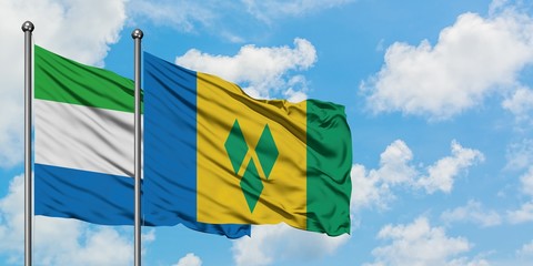 Sierra Leone and Saint Vincent And The Grenadines flag waving in the wind against white cloudy blue...