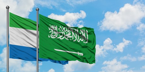 Sierra Leone and Saudi Arabia flag waving in the wind against white cloudy blue sky together....