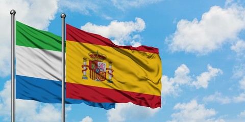 Sierra Leone and Spain flag waving in the wind against white cloudy blue sky together. Diplomacy concept, international relations.