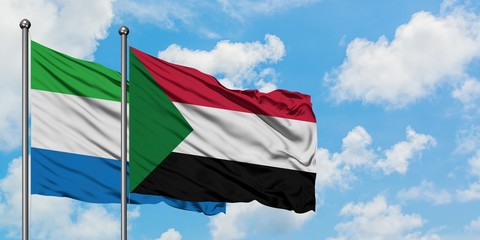 Sierra Leone and Sudan flag waving in the wind against white cloudy blue sky together. Diplomacy...