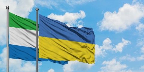 Sierra Leone and Ukraine flag waving in the wind against white cloudy blue sky together. Diplomacy...
