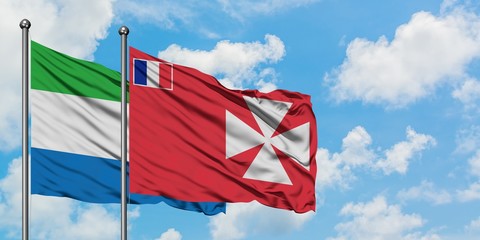Sierra Leone and Wallis And Futuna flag waving in the wind against white cloudy blue sky together....