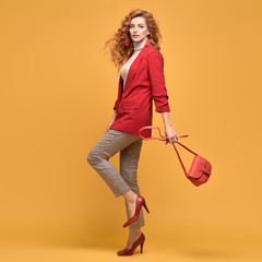 Fashionable woman in Trendy red outfit, stylish wavy hair, makeup. Joyful lady in jacket smiling...
