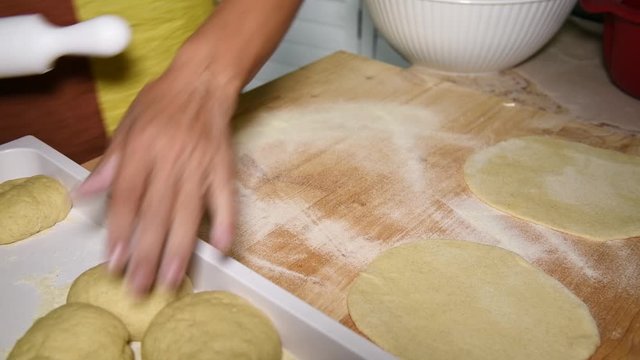 Female hands roll out the dough for pies. Cooking Apulian Panzerotti Patties Filled with Tomato, Mozzarella and Prosciutto. Panzerotti is a traditional dish in Salento, Puglia, fried in olive oil