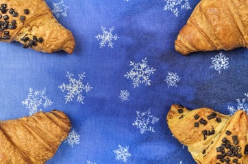 Background concept with sweet food. Golden croissants on a blue winter background.