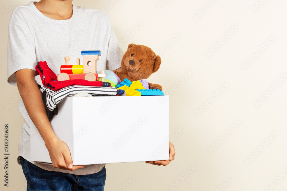 Wall mural Donation concept. Kid hands holding donate box with books, clothes and toys - Wall murals