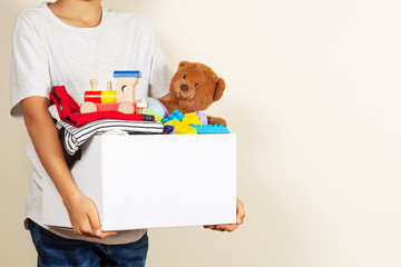 Donation concept. Kid hands holding donate box with books, clothes and toys