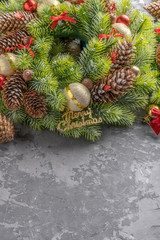 top view of Christmas wreath with fir, pine cones, balls , ribbons and acorns on concrete surface with copy space. Vertical view