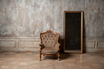 old chair and a mirror on the background of vintage wall