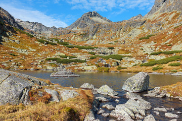 The lake above Skok waterfall (Pleso nad Skokom) in High Tatras National Park with rocks in the water and peaks in the background, in Slovakia © andras_csontos