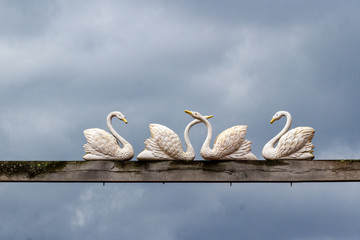 Group of carved swans balancing on a beam