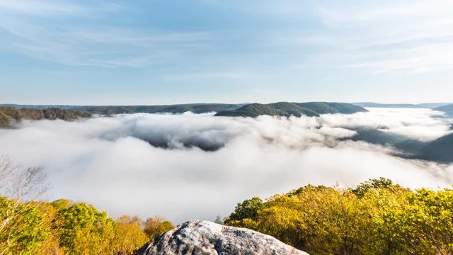 Timelapse of floating moving fog clouds during morning sunrise at Grandview Overlook in West Virginia WV with autumn foliage loop cinemagraph