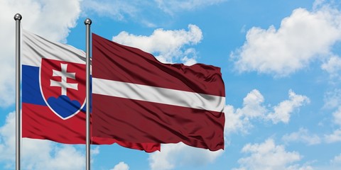 Slovakia and Latvia flag waving in the wind against white cloudy blue sky together. Diplomacy concept, international relations.