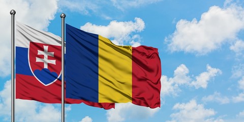 Slovakia and Romania flag waving in the wind against white cloudy blue sky together. Diplomacy concept, international relations.