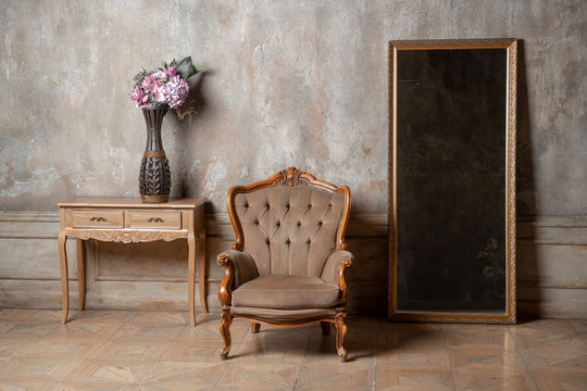 Old Chair, A Mirror And A Table With Flowers On Background Of Vintage Wall