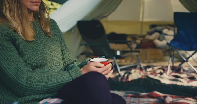 Young woman enjoying cup of coffee outside luxury tent