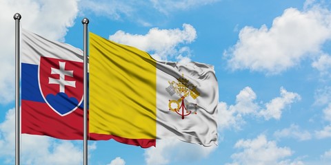 Slovakia and Vatican City flag waving in the wind against white cloudy blue sky together. Diplomacy...