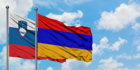 Slovenia and Armenia flag waving in the wind against white cloudy blue sky together. Diplomacy concept, international relations.