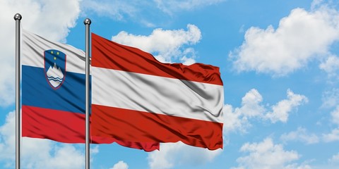 Slovenia and Austria flag waving in the wind against white cloudy blue sky together. Diplomacy concept, international relations.