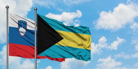 Slovenia and Bahamas flag waving in the wind against white cloudy blue sky together. Diplomacy concept, international relations.