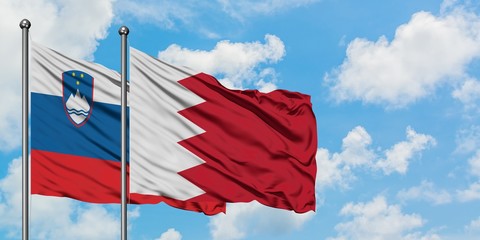 Slovenia and Bahrain flag waving in the wind against white cloudy blue sky together. Diplomacy concept, international relations.