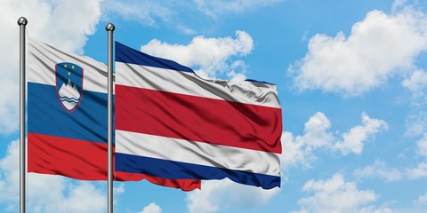 Slovenia and Costa Rica flag waving in the wind against white cloudy blue sky together. Diplomacy concept, international relations.