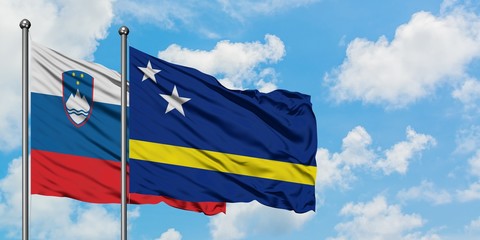 Slovenia and Curacao flag waving in the wind against white cloudy blue sky together. Diplomacy concept, international relations.