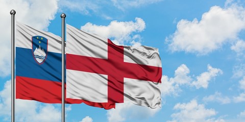 Slovenia and England flag waving in the wind against white cloudy blue sky together. Diplomacy concept, international relations.