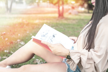 beautiful woman sitting reading book under the tree. young woman holding a book in the public park.
