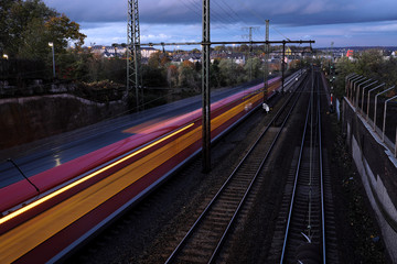 Fototapeta premium Personenzug mit Beleuchtung am Abend auf Bahnstrecke bei Koblenz - StockfotoJ