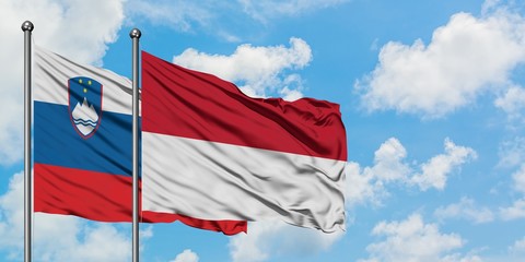 Slovenia and Indonesia flag waving in the wind against white cloudy blue sky together. Diplomacy concept, international relations.