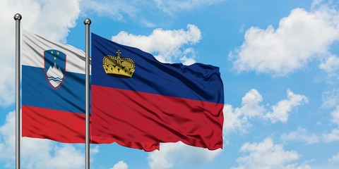 Slovenia and Liechtenstein flag waving in the wind against white cloudy blue sky together....