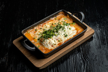 Cooked hot lasagna, in a beautiful cast-iron bowl.