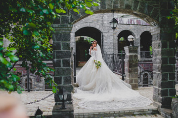 Young beautiful bride in luxury dress with a long train posing in country hotel