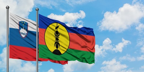 Slovenia and New Caledonia flag waving in the wind against white cloudy blue sky together. Diplomacy concept, international relations.