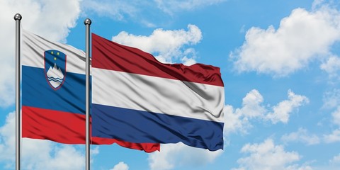 Slovenia and Netherlands flag waving in the wind against white cloudy blue sky together. Diplomacy concept, international relations.