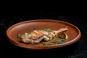 Grilled sea bass on a beautiful clay plate.