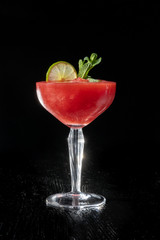 Strawberry daiquiri cocktail with lime, strawberry syrop, cherry and mint on black background.