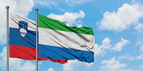 Slovenia and Sierra Leone flag waving in the wind against white cloudy blue sky together. Diplomacy concept, international relations.